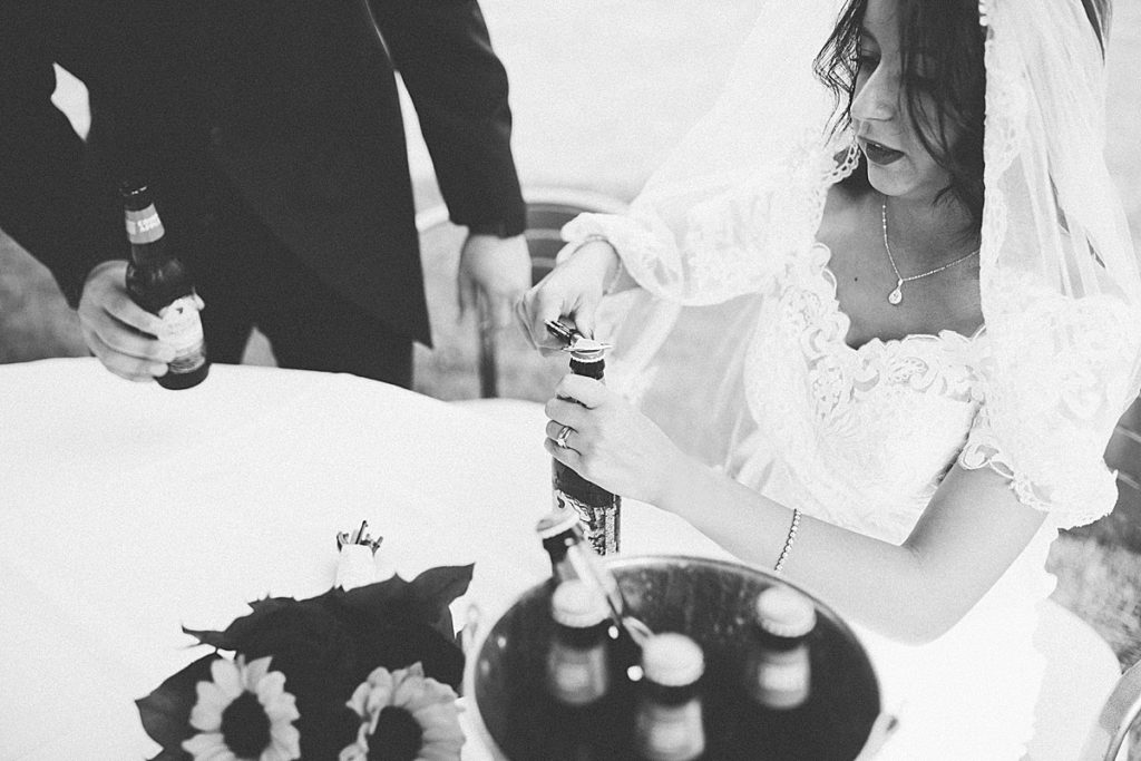 bride and groom opening a beer