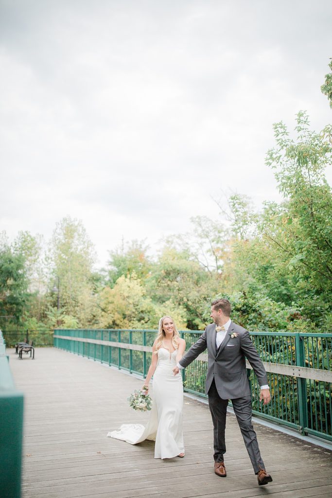 bride and groom walking across a bridge