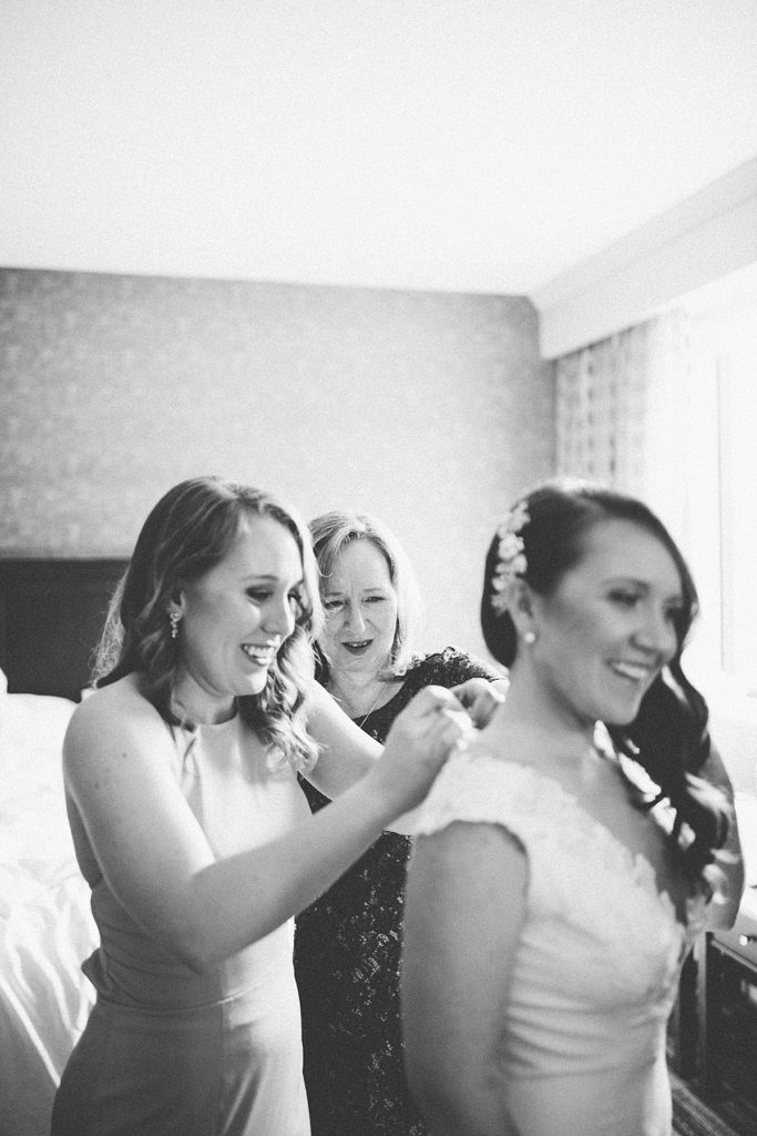 bride getting into her dress with her mom and sister helping