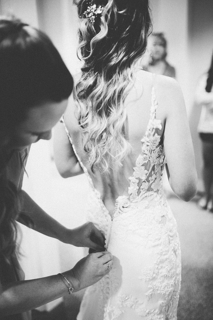 bride having her wedding dress buttoned up the back