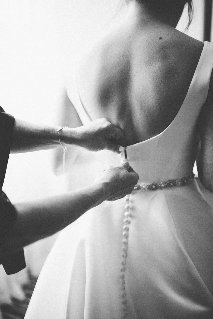 buttoning up the bride's dress