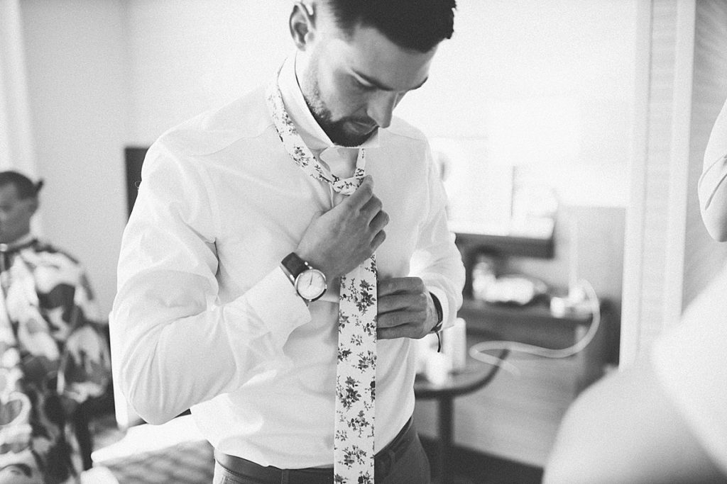 groom getting ready, tying his tie