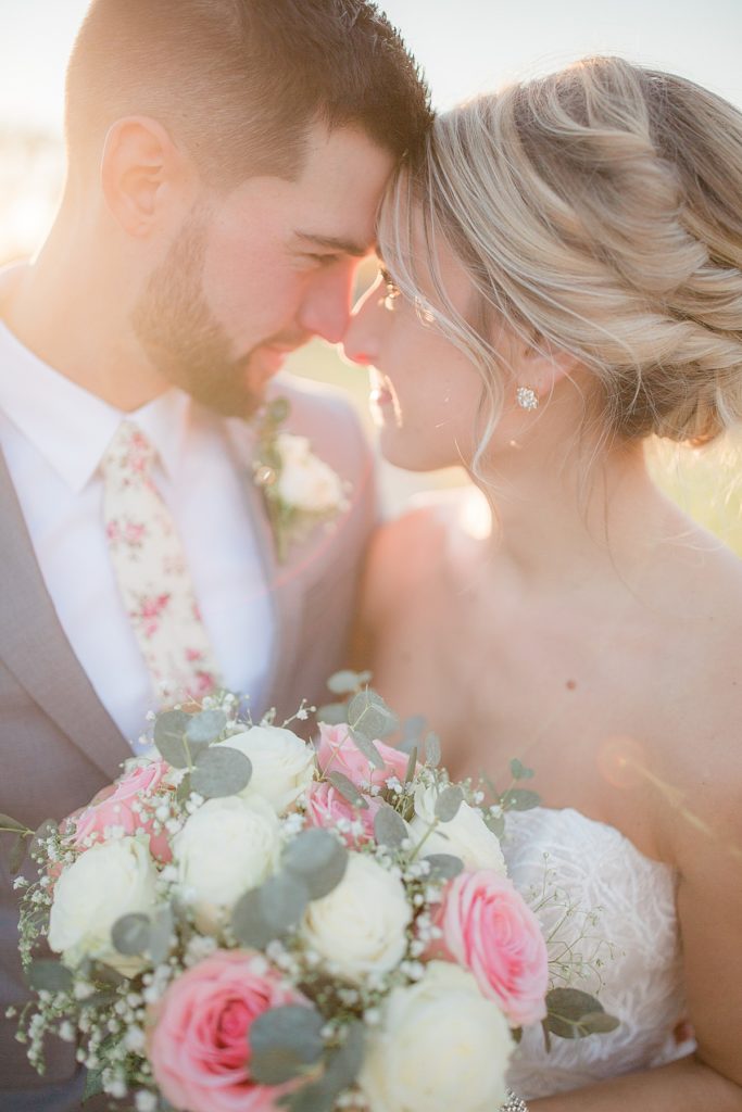 bride and groom touching foreheads during sunset