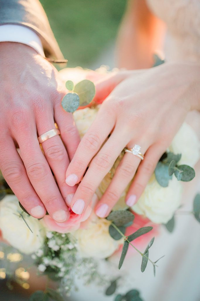 closeup of hands with rings on bridal bouquet