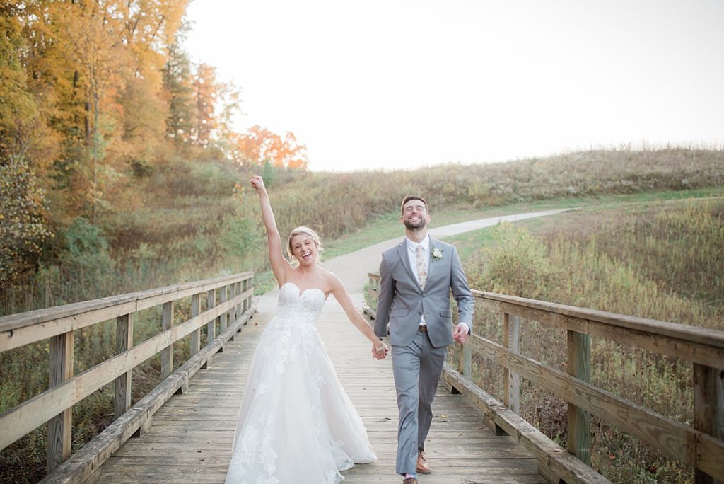 bride and groom walking across bridge