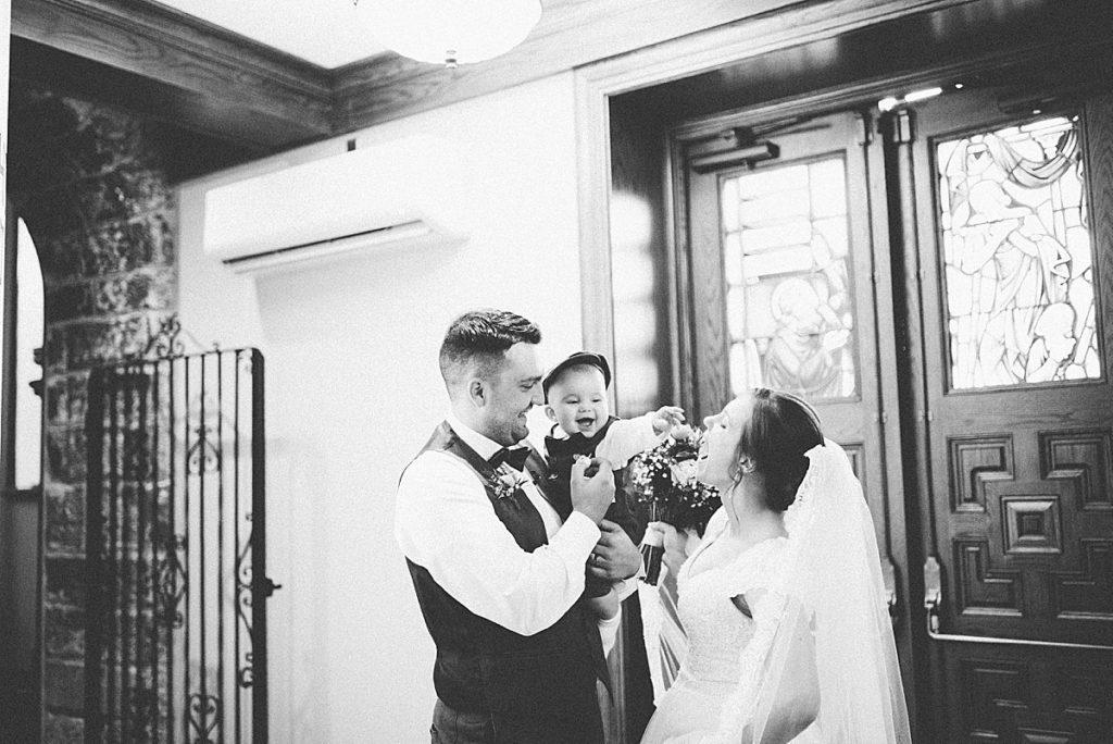 bride and groom kissing their child