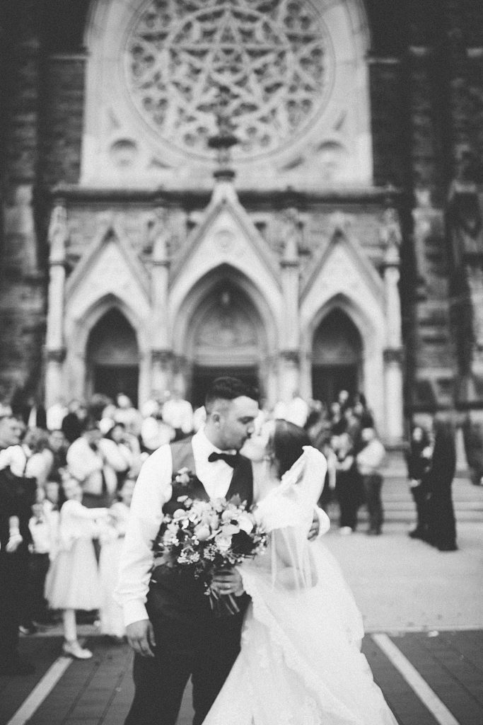 bride and groom kiss outside the church