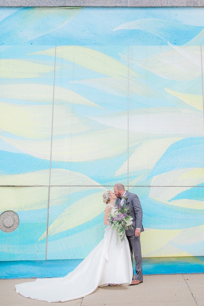 bride and groom kiss in front of a painted wall