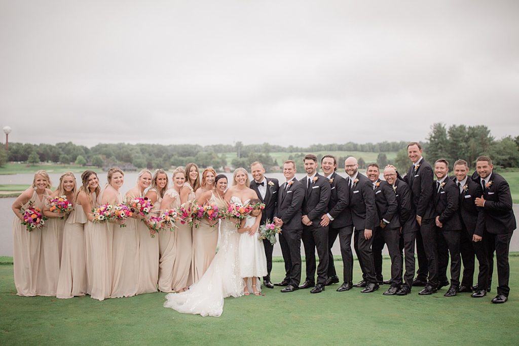 the wedding party stands on the golf course of firestone country club