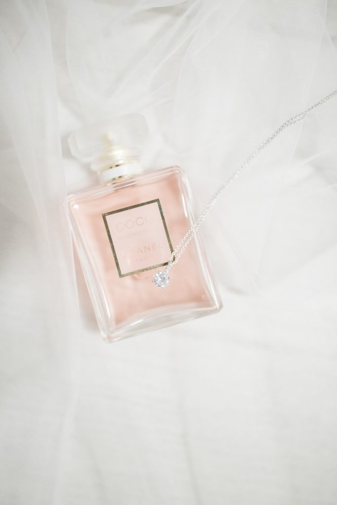 detail shot of the bride's perfume with the necklace on top under the veil
