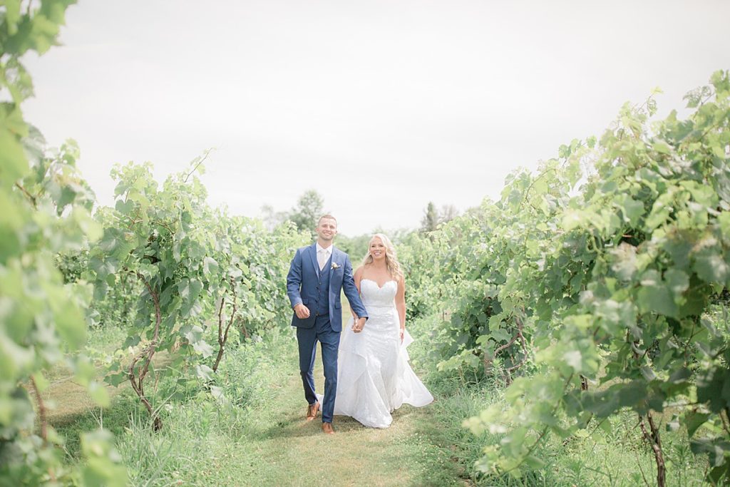candid shot of the bride and groom walking in the vineyards
