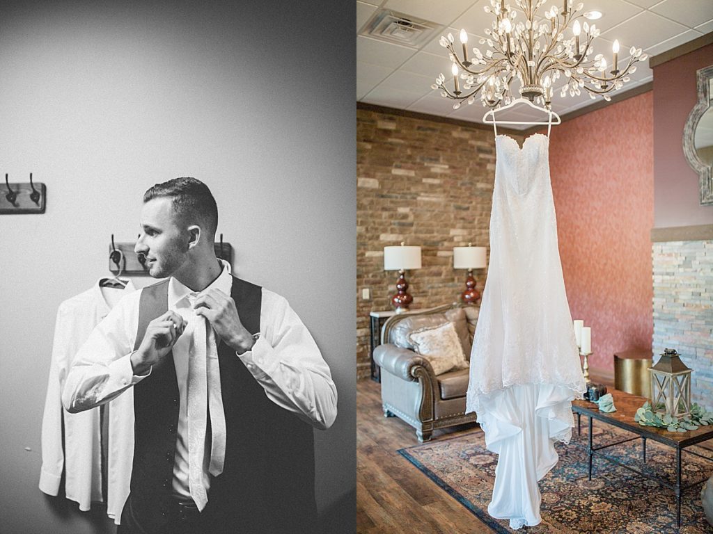 close up of groom fixing his tie and bride's dress hanging from the chandelier