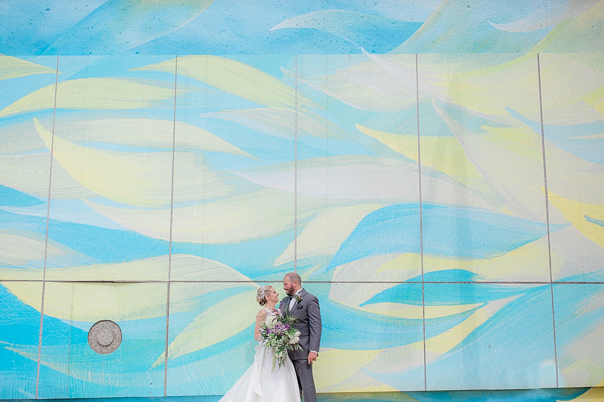 Bride and Groom by a blue and yellow mural wall