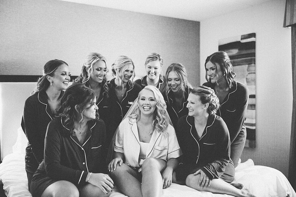 candid shot of bride and bridesmaids on the bed in their robes